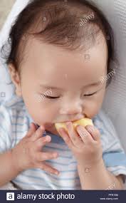 Baby Boy 6 Months Eating Piece Of Fruit Stock Photo