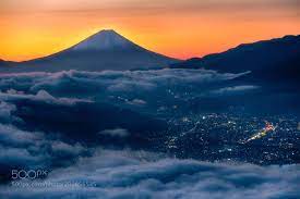 拂晓入秋后的富士山积雪面积越来越大伴随雨后平流雾的散开拂晓金色的光线中白雪盖头的富士山庄严肃穆逆光下的清晰身影一览无遗守候在100公里开外严寒结霜的高原上的人们顿时阵阵欢呼喜笑颜开了不起的大自然