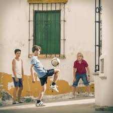 Un juego auténtico lleno de nobleza y emoción. Ninos Jugando Con Pelota De Futbol En El Callejon Tres Personas Equilibrio Stock Photo 199865736