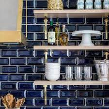 Hanging pendant bulb lights and warm floating wood shelves add warmth. Beveled Subway Tile Backsplash Design Ideas