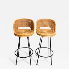 Stool features an oval woven rattan back, decorative nail trimming on the seat and gracefully flared legs. Danny Ho Fong Pair Of Vintage Swivel Woven Rattan Bar Stool 1960s