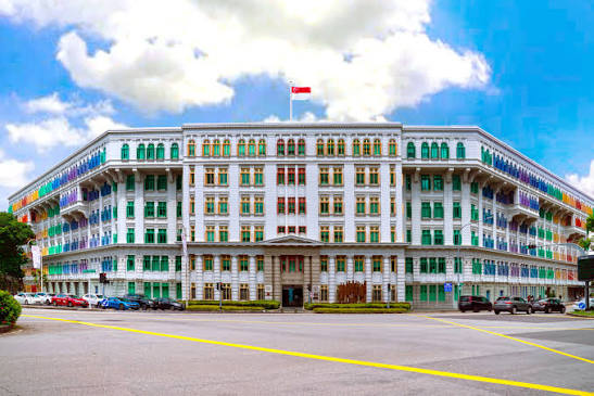 White corner building with multicoloured rainbow shutters and awnings