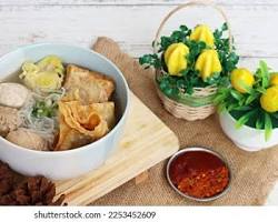 Gambar steaming bowl of Bakso Malang with various meatballs, tofu, and noodles.