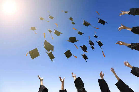 Happy young graduates throwing hats - Stock Image - Everypixel