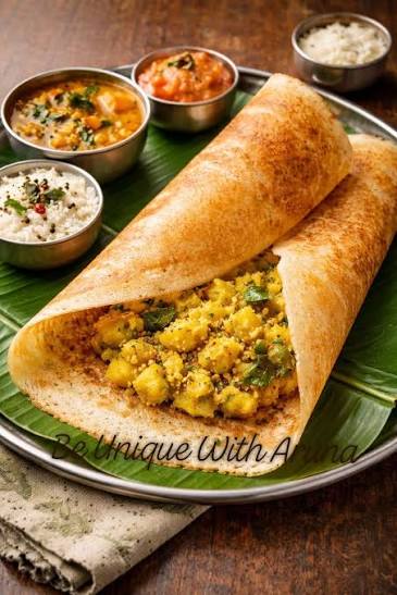 Crispy golden Indian dosa served with coconut chutney, sambar, and potato filling on a banana leaf