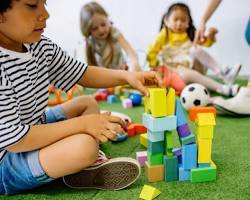 Image of diverse group of children playing with building blocks, books, and other toys