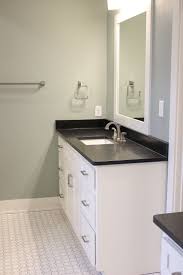 This double sink white bathroom vanity holds unique wooden sinks to match a wood bath. A Picture Of A Bathroom With White Tile White Cabinets And Black Gr White Cabinets White Countertops White Bathroom Cabinets White Cabinets Black Countertops