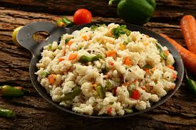 Upma served in a bowl garnished with coriander and lemon wedge