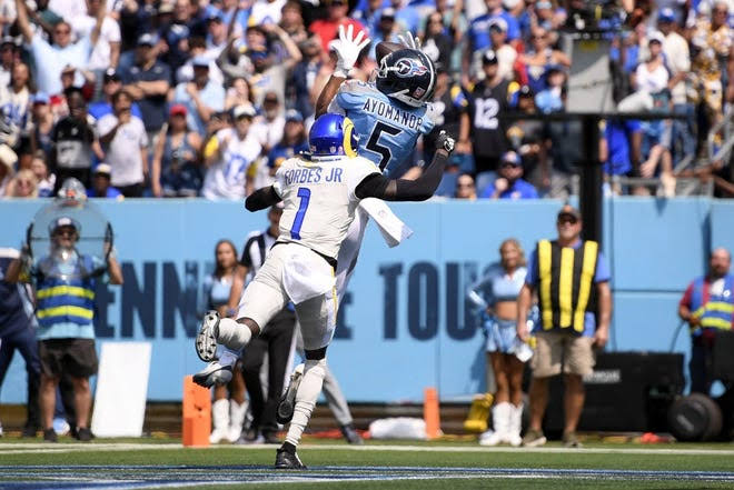 Titans receiver catches pass over defender in the end zone during game.