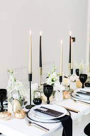 Black and white balloons, candles, blankets, napkins, dinner and appetizer plates, and cutlery are good ways to have black and white decorations. Black White And Gold Table Setting For A Chic All Hallows Eve Soiree Minimalist Halloween Table Decorations Dinner Party Table Settings Halloween Party Dinner