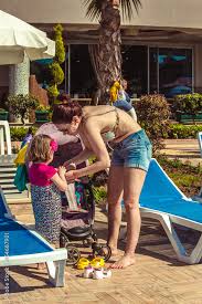 Mom and baby girl of European appearance near the chaise longue. Mom in  sunglasses helps the child to undress. The concept of a happy family who  came to rest. Stock Photo |