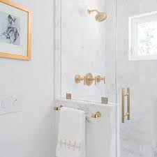 Black and white shower designed with mini black penny floor tiles and white subway wall tiles accented with a polished brass shower head. Lucite Shower Door Handle Design Ideas