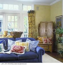 Family Room Denim Blue Sofa Fringed Pillows In Blue Toile Yellow Plaid And Red Floral Y French Country Living Room Country Living Room Country Style Sofas