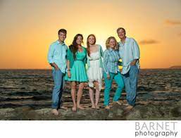 Sun on horizon at sunset with blue orange gradient sky and dark dramatic clouds over ocean. Beach Family Portrait At Sunset