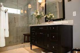 Chic contemporary bathroom design with gorgeous gray paneled walls and mirrored wall treatment with hollywood wall sconces and glamorous touches in a magnificent gray double sink vanity with beveled calcutta marble countertops and concave hardware with an undermount sink with polished nickel faucets. La Dolce Vita Jeff Lewis Design Black Vanity Bathroom Jeff Lewis Design Grey Bathrooms
