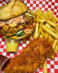 A plate with crispy fries and a juicy burger with lettuce and tomato on a white background