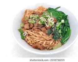 Gambar Cwie Mie Pelangi, a bowl of noodles with colorful noodles in shades of red, yellow, green, and blue, topped with chicken, vegetables, and dumplings.