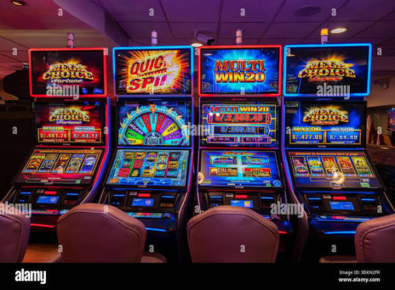 Row of illuminated slot machines in a modern casino with bright, colorful screens and neon lights Stock Photo - Alamy