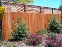 A cedar fence featuring square lattice and chunky posts creates a decorative yard. Diagonal Square Lattice Arbor Fence Inc A Diamond Certified Company