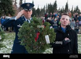 U.S. Air Force Col. Kirk Peterson, 673d Logistics Readiness Group  commander, salutes a wreath he placed with Gold Star family member Nicholas  Strobbe, during the annual Wreaths Across America day at the