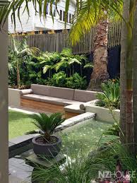 Tropical Courtyard Garden With A Water Feature And Built In Alfresco Sofa Sloped Backyard Landscaping Sloped Backyard Backyard Landscaping Designs