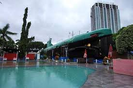 Monumen kapal selam atau yang seirng disebut monkansel, dilihar dari seberang sebuah sungai di surabaya. Berwisata Sejarah Ke Monumen Kapal Selam Surabaya