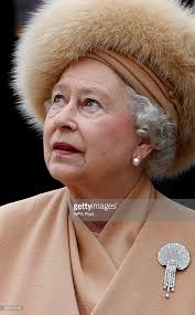 Britain's Queen Elizabeth II looks up at the statue of her mother as...