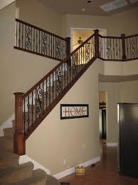 Stairs are underneath a hanging chandelier with shades. Maple Wood Railing With Box Newel And Scroll Panels Wrought Iron Wrought Iron Stair Railing Wrought Iron Stairs Stair Railing Design