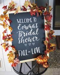 White pumpkins and candles are a chic and stylish decor idea for a neutral fall bridal shower. Chalkboard Welcome Sign To Bridal Shower Fall In Love Theme Bridal Shower Decorations Rustic Wedding Shower Themes Unique Bridal Shower Themes