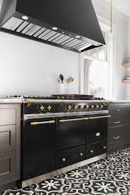 A Lacanche Range Sits On A Black And White Cement Floor Tiles Between Black Shaker Drawers Adorned With Brass Pulls And A White Quartz Cuisines De Reve Idee Cuisine Et