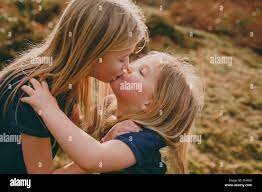 Two cute blond sisters kissing outdoors Stock Photo - Alamy