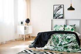 The bed features a black and white comforter with a simple flower pattern accompanied by black, white, and shiny green pillows. 50 Of The Most Spectacular Green Bedroom Ideas The Sleep Judge