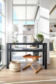 A Serena Lily Cooper Leather Stool Sits Beneath A Styled Black Tiered Console Table Lit By A Glass And Brass Dou Black Console Table Interior Design Interior