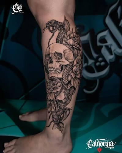 Skull & snake calf tattoo 🐍💀 striking black and grey piece featuring a detailed skull wrapped in a flowing snake, surrounded by soft floral elements. smooth shading and fine linework create a