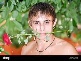 young handsome guy with a red rose in his mouth Stock Photo