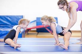 The girls' leotards featured here are perfect for gymnastics practice and are made with breathable fabrics that are great for training in the gym. Three Girls Doing Gymnastics Exercise On Floor Stockphoto