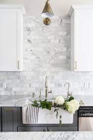 The transitional kitchen's masterpiece is the gorgeous hood with a great island! Two Toned Gray And White Cabinets Marble Subway Tile Carrara Countertops A Big Farmhouse Sink And Br White Marble Kitchen Kitchen Renovation Kitchen Marble