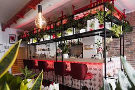 Start with dark wood shelving a clean bar top with a unique texture and comfortable stools. Bar Atelier Stil Manipulation