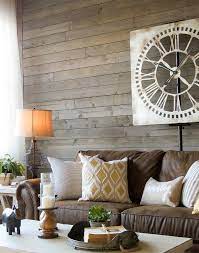 Achieving a farmhouse living room is easy if you keep comfort in mind. Love This Farmhouse Living Room With A Brown Sofa Rustic Gray Wood Walls Warm White Ta Brown Couch Living Room Farm House Living Room Brown Living Room Decor