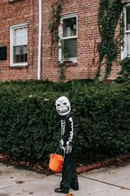 Unrecognizable Kid In Scary Skeleton Costume Standing Outside Brick House Free Stock Photo