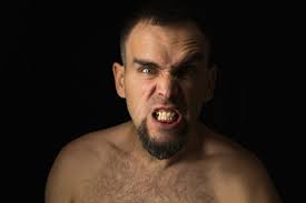 Retrato De Un Joven Enojado Con La Boca Abierta Y Los Dientes Apretados.  Hombre Caucásico Con Barba Sin Camisa Sobre Fondo Negro. Ira, Agresión Y  Rabia En Un Rostro Humano Fotos, retratos,