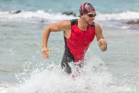 Triathlon Swimming Man. Male Triathlete Swimmer Running Out Of Ocean  Finishing Swim Race. Fit Man Ending Swimming Sprinting Determined Out Of  Water In Professional Triathlon Suit Training For Ironman. Stock Photo,  Picture