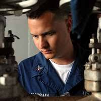 A black and white photo of a man wearing a hard hat. Office of War  Information Photograph