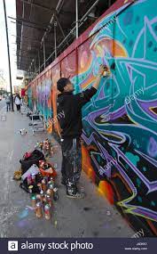 Street Artist Spray Painting Graffiti Mural On Hoarding Along Great Eastern Street Shoreditch East London Uk Stock Photo Alamy