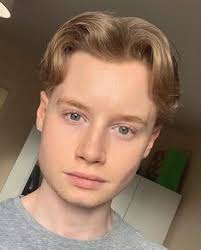 The hairstyle is parted down the middle with curtain bangs framing either side of the face. Eboy Haircut