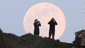 Crowds look on as the supermoon rises behind the fremantle war memorial at monument hill in fremantle, australia. Dhpfuwkyeqapmm