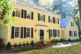Yellow colonial house with black shutters. Young House Love House Crashing Cozy And Full Of Character Https Www Younghouselove Yellow House Exterior Colonial House Exteriors House Paint Exterior