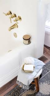 It is a brass/gold metal (polished brass) and a modern shape. Tub Shower Reveal With Modern Polished Brass Fixtures Made By Carli