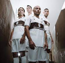 Una de ellas es sólida y la otra despliega finísimas líneas verticales. Camiseta Kelme De Platense 2021