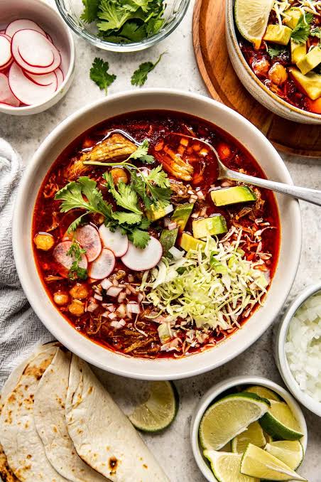 Large pot of pozole rojo simmering on the stove - Mexican hominy stew recipe
